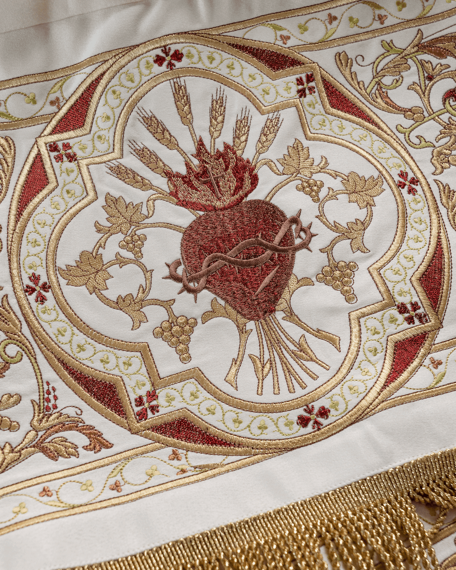 Haft Najświętszego Serca Pana Jezusa w koronie cierniowej z płomieniem i krzyżem, w czworolistnej ramie wypełnionej ornamentem z winorośli i kłosów pszenicy, nici złote i czerwone